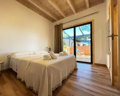 a bedroom with two beds and a sliding glass door at Apartamentos Biopasivos Living Pura Madera in Chiclana de la Frontera