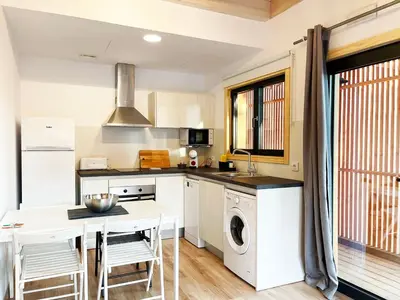 a kitchen with white cabinets and a table with chairs at Apartamentos Biopasivos Living Pura Madera in Chiclana de la Frontera