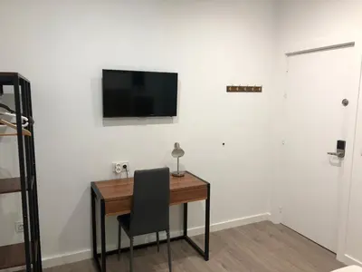 a desk with a chair and a television on a wall at La Estación in Sanlúcar de Barrameda