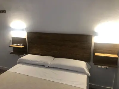 a bedroom with a bed with two pillows and two lights at La Estación in Sanlúcar de Barrameda