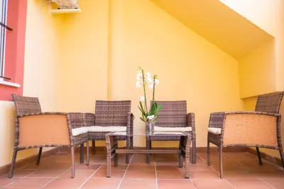 a table with chairs and a vase with flowers on it at Apartamento AGUASAL in Sanlúcar de Barrameda