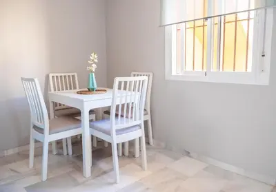 a white dining room table with four chairs and a window at Apartamento AGUASAL in Sanlúcar de Barrameda