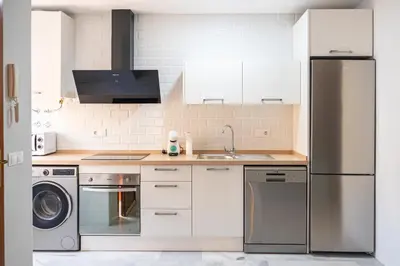 a kitchen with white cabinets and a stainless steel refrigerator at Apartamento AGUASAL in Sanlúcar de Barrameda