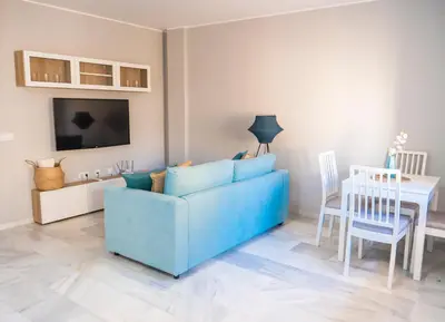 a living room with a blue couch and a table at Apartamento AGUASAL in Sanlúcar de Barrameda