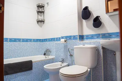 a blue and white bathroom with a toilet and a sink at Apartamento AGUASAL in Sanlúcar de Barrameda