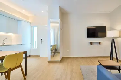 a living room with a table and a tv on a wall at Tandem Pópulo in Cádiz
