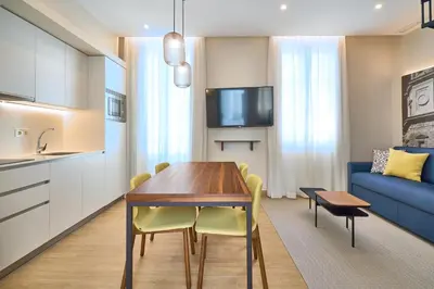 a kitchen and living room with a table and a blue couch at Tandem Pópulo in Cádiz