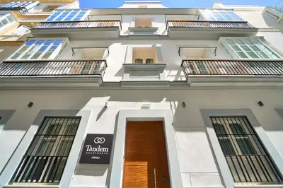 a tall white building with a door and windows at Tandem Pópulo in Cádiz