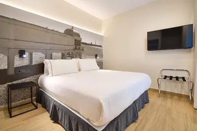 a bedroom with a large white bed and a flat screen tv at Tandem Pópulo in Cádiz