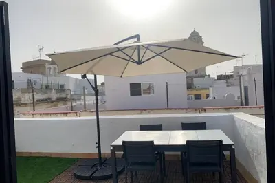 a table and chairs with an umbrella on a roof at Hidden Gem Penthouse Populo y Catedral in Cádiz