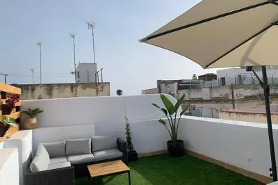 a patio with a couch and an umbrella on a roof at Hidden Gem Penthouse Populo y Catedral in Cádiz