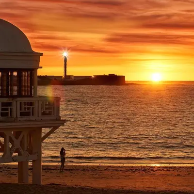 a person standing on the beach at sunset at Caleta Dreams. Apartamento a estrenar. A 60 metros Playa in Cádiz