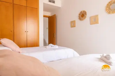 two beds in a bedroom with white sheets at Casa Capuchinos - FREE PARKING by Cadiz Time in Cádiz