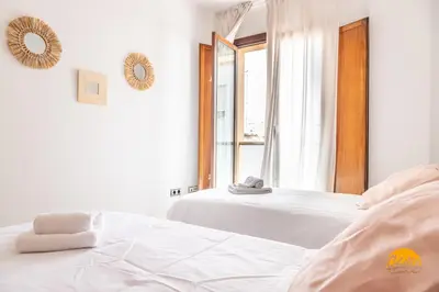 a white bedroom with two beds and a window at Casa Capuchinos - FREE PARKING by Cadiz Time in Cádiz
