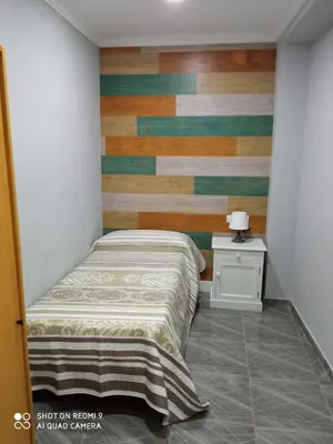 a bedroom with a bed and a wooden accent wall at Casa La Maravilla in Jerez de la Frontera