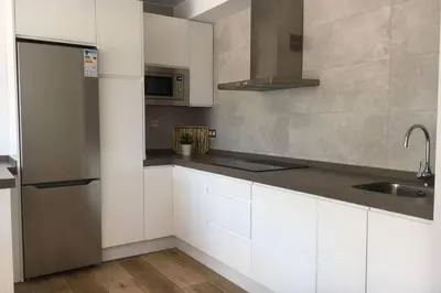 a kitchen with white cabinets and a stainless steel refrigerator at Apartamento a estrenar en un lugar emblemático in Conil de la Frontera