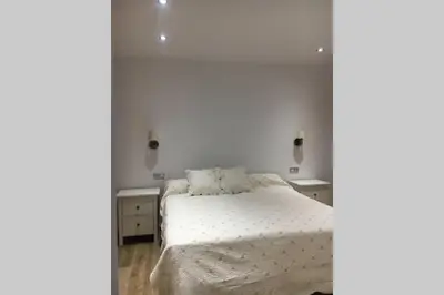a white bedroom with a bed and two dressers at Apartamento a estrenar en un lugar emblemático in Conil de la Frontera
