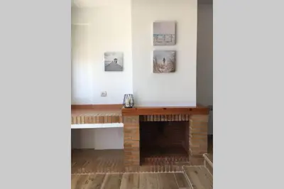 a living room with a fireplace and pictures on the wall at Apartamento a estrenar en un lugar emblemático in Conil de la Frontera