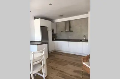 a kitchen with white cabinets and a table and chairs at Apartamento a estrenar en un lugar emblemático in Conil de la Frontera