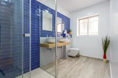 a blue tiled bathroom with two sinks and a toilet at TACITA Family Home by Cadiz4Rentals in Cádiz