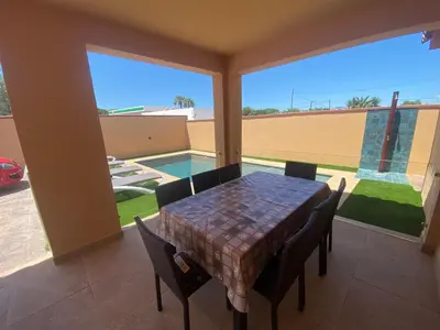 a dining room with a table and chairs and a pool at Villa Raquel in Conil de la Frontera