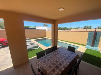 a dining room with a table and a view of a pool at Villa Raquel in Conil de la Frontera