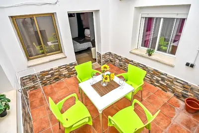 a patio with a table and green chairs at Plaza Noria Apartments with Balconies in El Puerto de Santa María