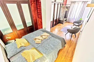 a bedroom with a bed and a chair in a room at Plaza Noria Apartments with Balconies in El Puerto de Santa María