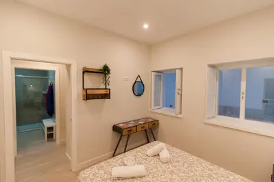 a bedroom with a bed and a table and windows at Apartamento - Patio 1812 in Cádiz