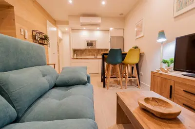 a living room with a blue couch and a kitchen at Apartamento - Patio 1812 in Cádiz