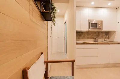 a kitchen with white cabinets and a table and a chair at Apartamento - Patio 1812 in Cádiz