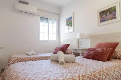 a bedroom with two beds and two windows at El Embrujo de La Caleta by Gades Gestión in Cádiz