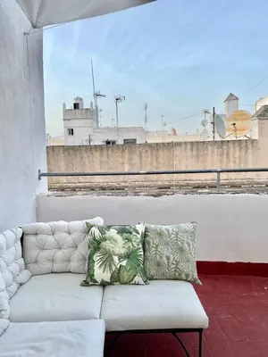a couch on a balcony with a view of a building at Apartamentos la Selva - Rafael de la Viesca in Cádiz