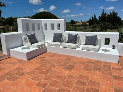 a white bench with pillows on it on a patio at Studio La Maravilla 1001 Nacht, Playa La Barrosa in Chiclana de la Frontera