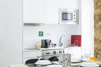 a white kitchen with a table and a microwave at El Arco del Fotografo by Cadiz Time in Cádiz