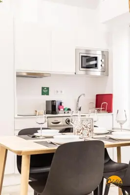 a kitchen with a table and chairs and a kitchen with white cabinets at El Arco del Fotografo by Cadiz Time in Cádiz