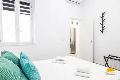 a white room with a bed with green pillows at El Arco del Fotografo by Cadiz Time in Cádiz