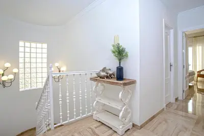 a white staircase in a home with a vase on a table at Genteel Home Mirador de La Barrosa in Chiclana de la Frontera