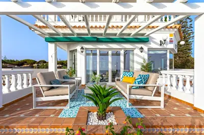 a pergola on a patio with chairs and a plant at Genteel Home Mirador de La Barrosa in Chiclana de la Frontera