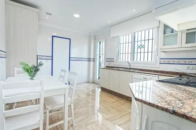 a kitchen with white cabinets and a white table and chairs at Genteel Home Mirador de La Barrosa in Chiclana de la Frontera