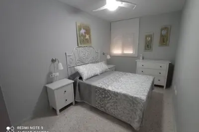 a white bedroom with a bed and a nightstand and a bed sidx sidx sidx at Apartamento cabañiles wifi in Jerez de la Frontera