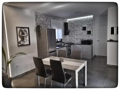a kitchen with a table and chairs and a refrigerator at Sirocco in Chiclana de la Frontera