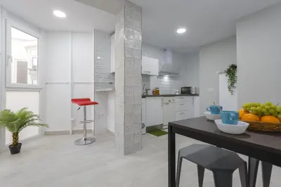 a white kitchen with a table and a red chair at ATLANTICO Family Home by Cadiz4Rentals in Cádiz