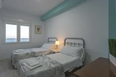 a room with two beds and a table and two windows at ATLANTICO Family Home by Cadiz4Rentals in Cádiz