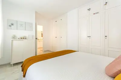a white bedroom with a bed and a kitchen at Sherryflat Atípika in Jerez de la Frontera