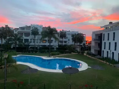 a swimming pool with umbrellas in a yard with buildings at Apartamento La Sirenita in Rota