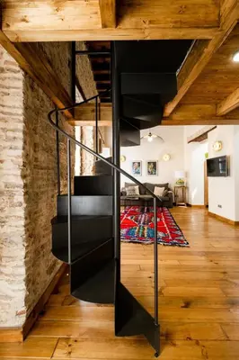 a black spiral staircase in a living room at La Posada de Juan in Cádiz