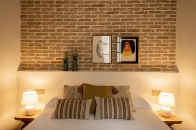 a bedroom with a brick wall and a bed with two lamps at La Posada de Juan in Cádiz