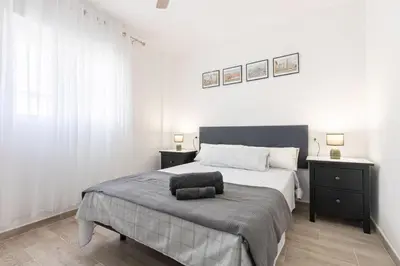 a white bedroom with a large bed and two night stands at RONDA DE MULEROS 6 in Jerez de la Frontera