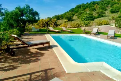 a swimming pool with chaises and chairs next to a resort at Villa exclusiva con piscina privada, La Tina Golf in Arcos de la Frontera